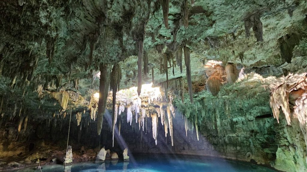 Cenote de agua turquesa con estalactitas iluminadas por la luz natural en Yucatán